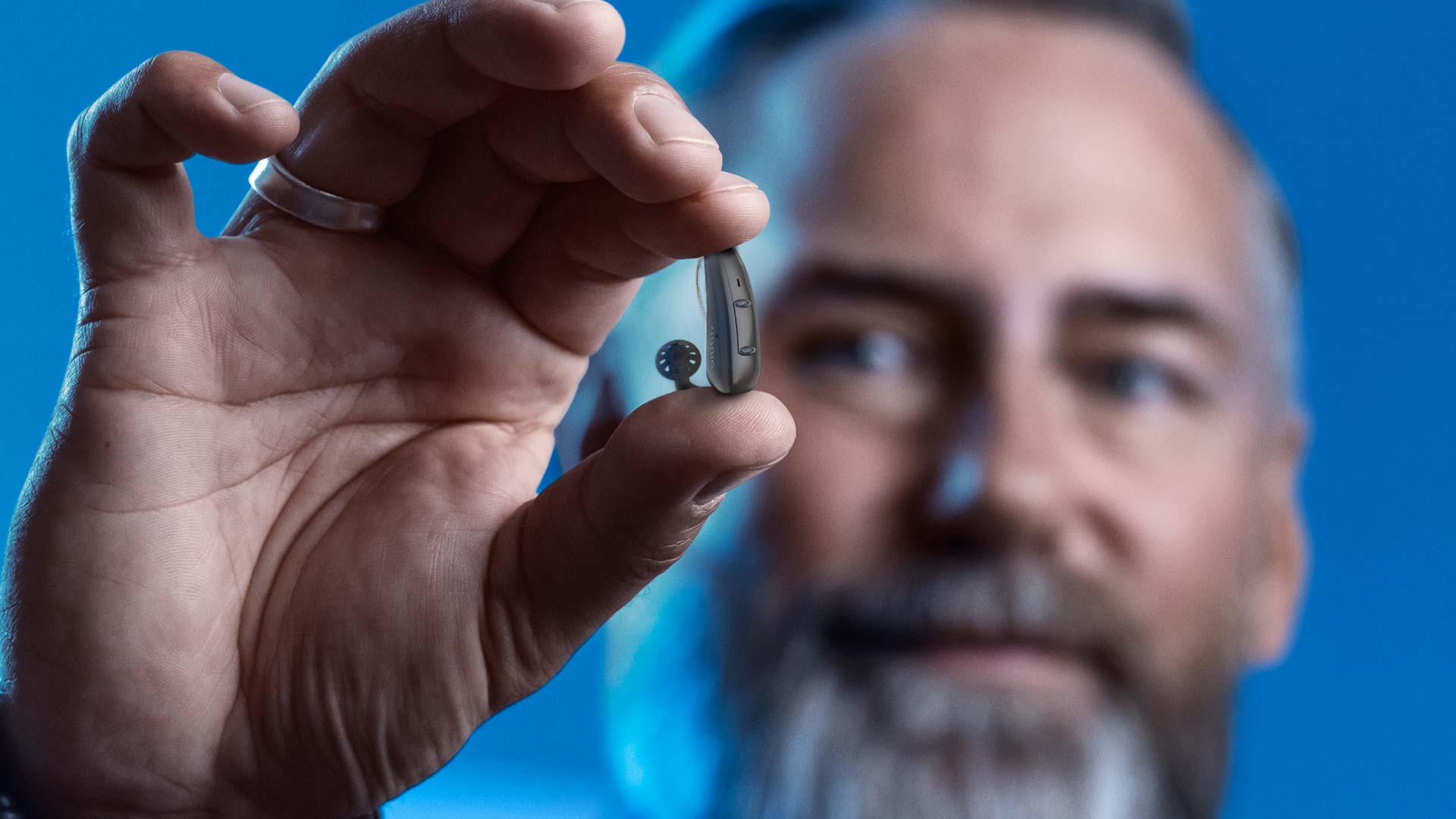 Man with beard holding Signia Pure Charge&Go hearing aid
