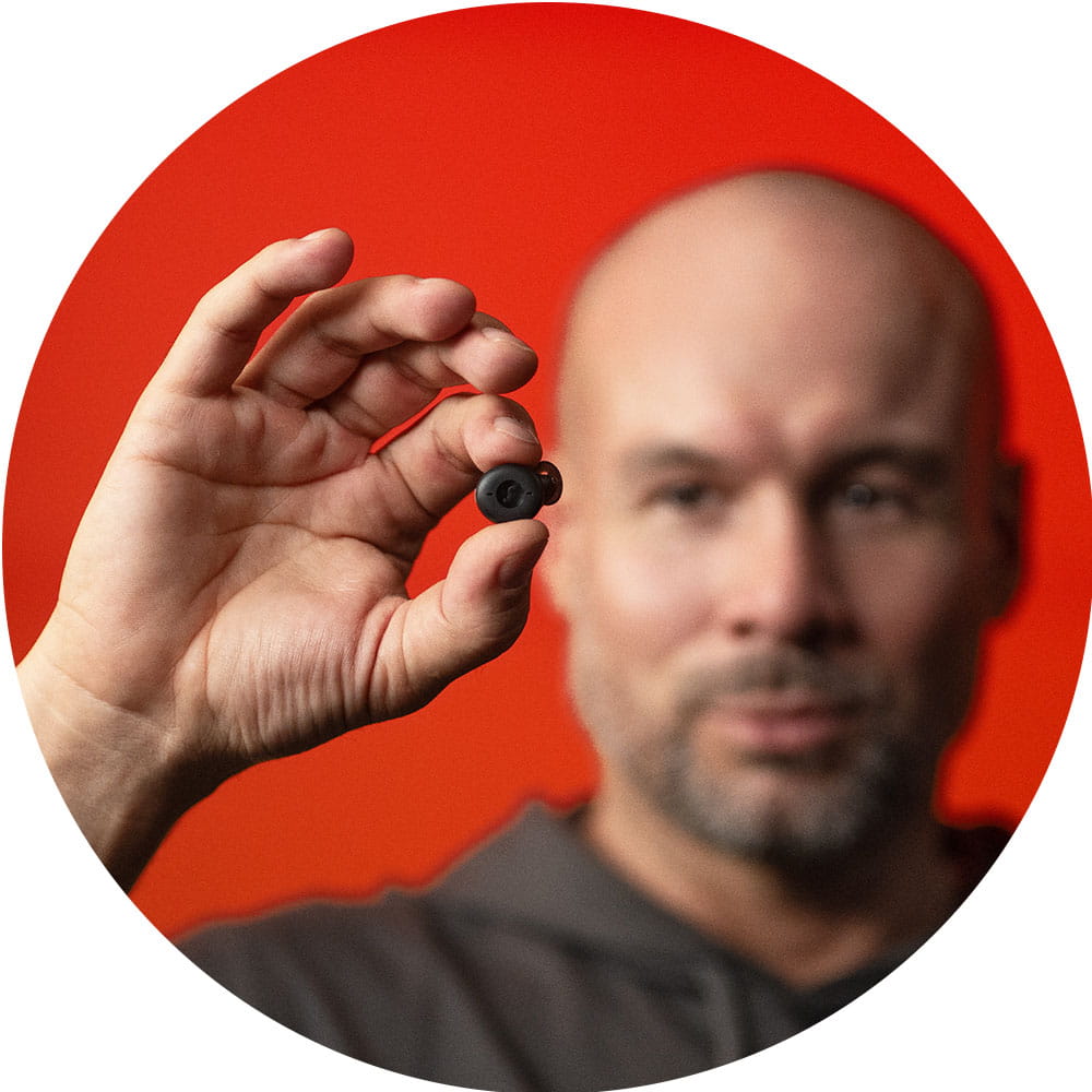 Man holding Active IX hearing aid in earbud design