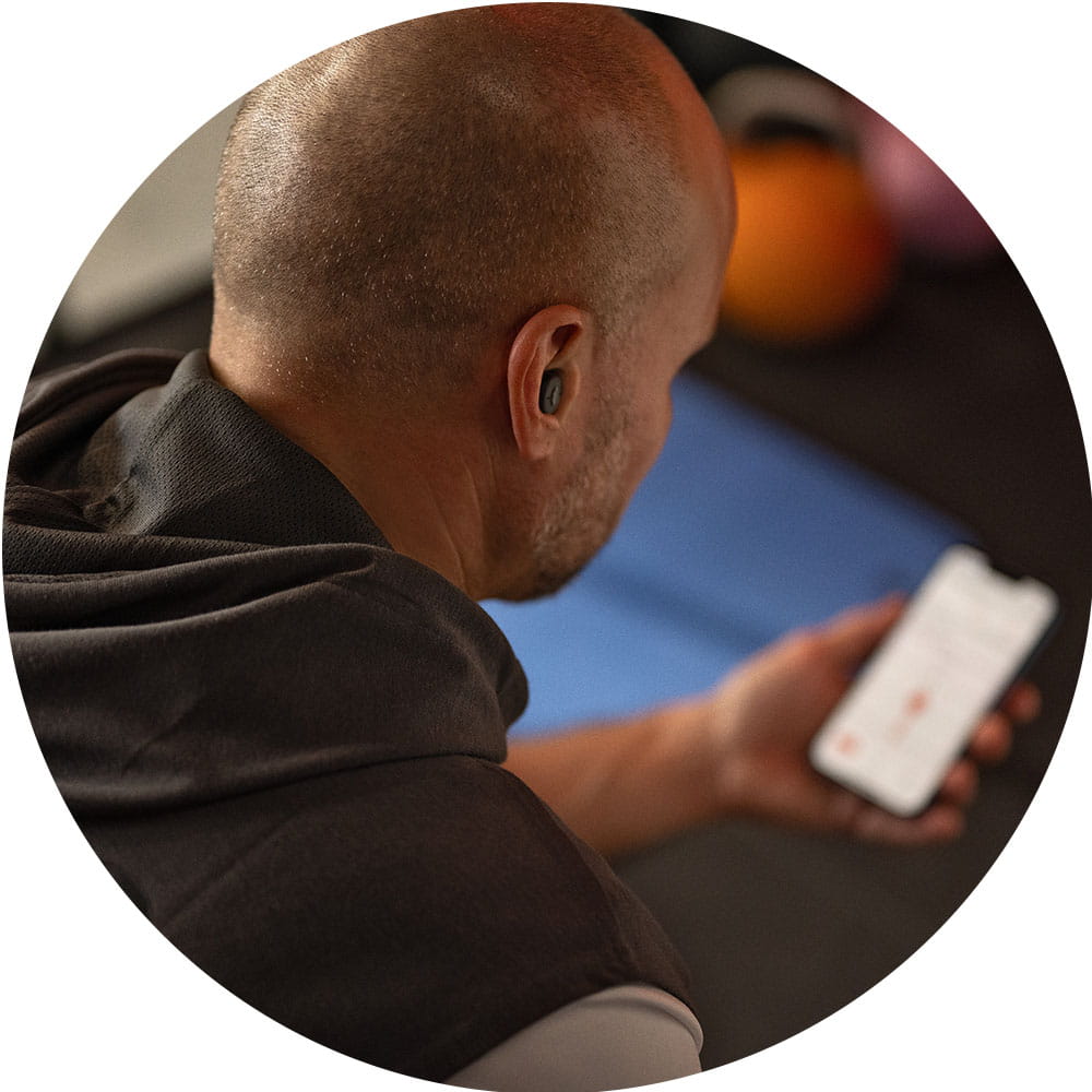 Man controls his Active IX hearing aids in earbud design with a smartphone