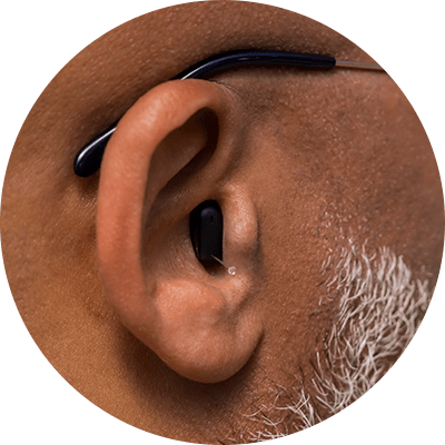 gros plan sur l'oreille d'un homme de couleur, équipé d'aides auditives invisibles et sans pile signia silk charge and go ix